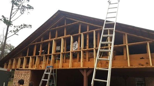 Level Headed Construction framing a large room addition onto an existing brick home — new walls and roof rafters going up