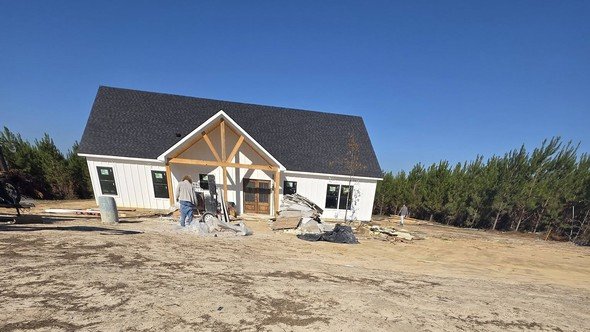 A finished modern farmhouse custom home built by Level Headed Construction in the Lake Houston area — white board-and-batten siding and a timber-truss covered front porch