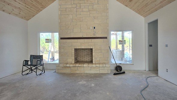 Interior of a custom home by Level Headed Construction — vaulted tongue-and-groove great room with a floor-to-ceiling stone fireplace