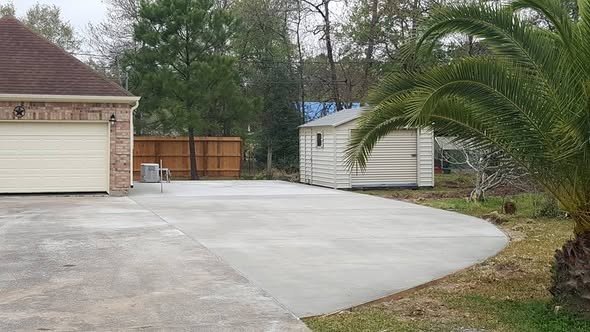 A wide concrete driveway poured and finished by Level Headed Construction in front of a two-car garage in the Lake Houston area