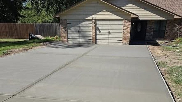 A fresh concrete driveway by Level Headed Construction running from the street up to the garage, finished smooth with control joints