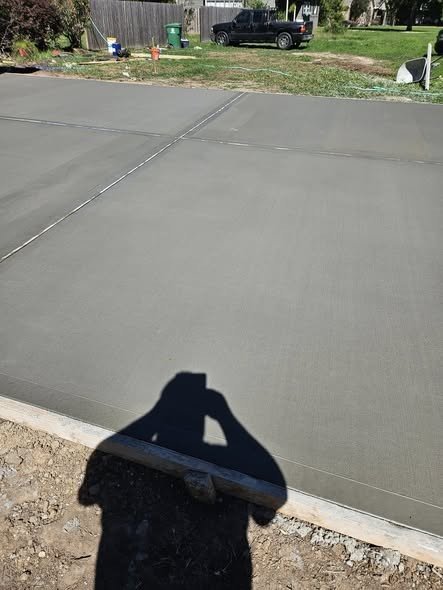 A finished, broom-textured concrete foundation slab beside a fresh pour in the Lake Houston area