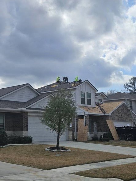A Level Headed Construction crew re-roofing a storm-damaged two-story home with boarded-up windows and a tear-off dumpster on site, in the Huffman / Lake Houston area
