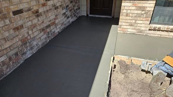 A new concrete front-entry walkway and porch poured by Level Headed Construction up to a home's front door