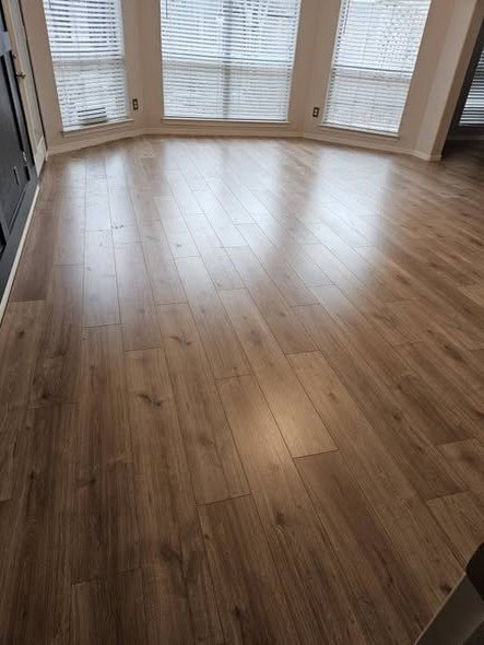 A living area with fresh wide-plank flooring and a bay window, remodeled by Level Headed Construction
