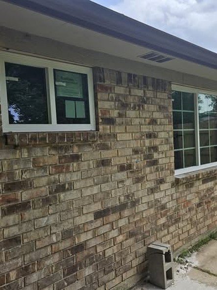 Two newly installed white windows set into a brick wall, trimmed clean, on a home in the Lake Houston area