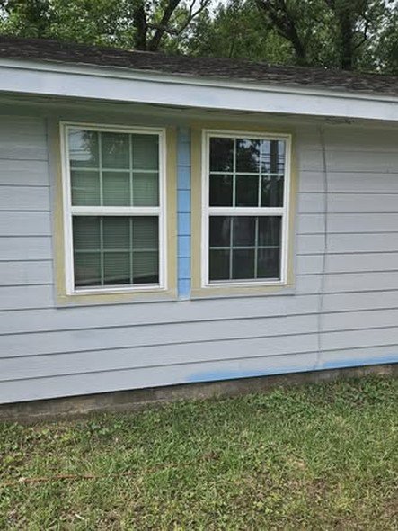 Two new white double-hung windows installed in gray lap siding, flashed and trimmed, on a home in the Huffman area